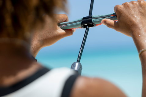Duotone Click Bar Quad Control kite control bar during kitesurfing on the ocean in teal and coral