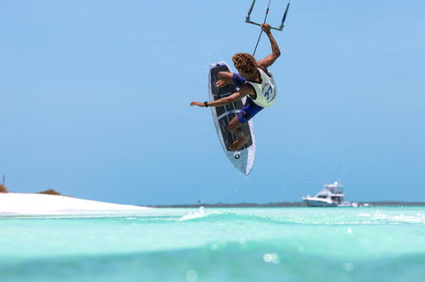 Duotone Click Bar Quad Control bar during kitesurfing aerial maneuver over tropical turquoise water