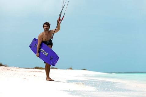 Tabla de kitesurf twin-tip Duotone Jaime SLS en violeta durante kitesurf en playa tropical