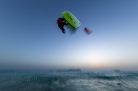 Tabla de kitesurf twin-tip Duotone Jaime Concept Blue durante un salto de kitesurf sobre el océano al atardecer