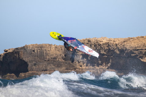 Duotone Cosmic D/LAB windsurf wave board during wave riding at a rocky coastline