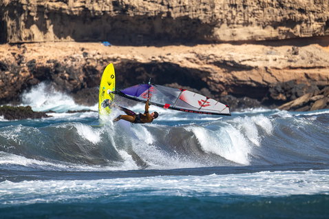 Duotone Cosmic D/LAB wave windsurf board during wave riding at a rocky coastline