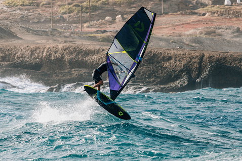 Duotone Skate D/LAB freestyle windsurf board during freestyle windsurfing at a rocky coastline