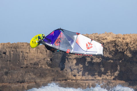 Duotone Super Hero D/LAB wave sail during wave windsurfing at a rocky coastal cliff