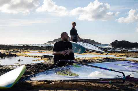 Duotone Super Hero D/LAB wave windsurf sail during wave riding at a rocky coastal shore