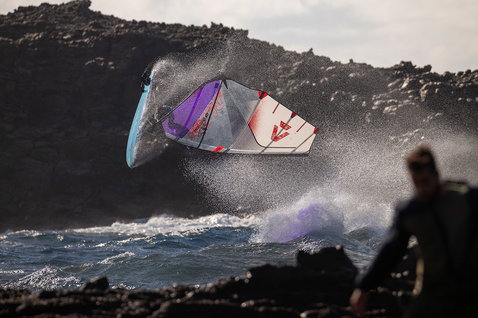 Duotone Super Hero D/LAB wave windsurf sail during wave riding at a volcanic coastline