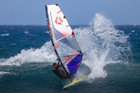 Duotone Super Hero D/LAB wave windsurf sail during wave riding on the ocean in white, navy and red