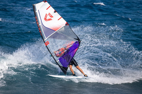 Duotone Super Hero D/LAB wave windsurf sail during wave riding on the ocean in navy, purple and white