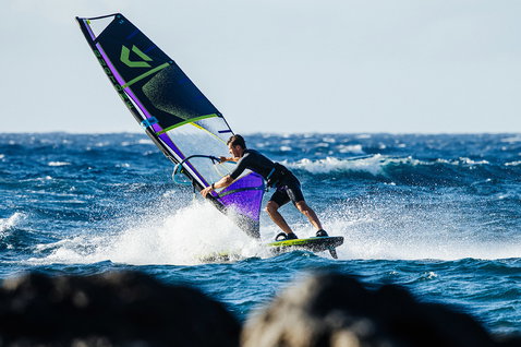 Duotone Idol freestyle windsurf sail during windsurfing on the ocean in black, violet and lime green