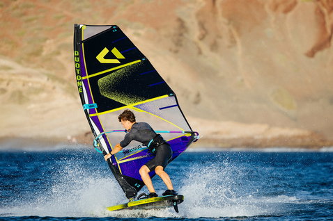 Duotone Idol freestyle windsurf sail 4.8m² in black and violet during windsurfing at the coast