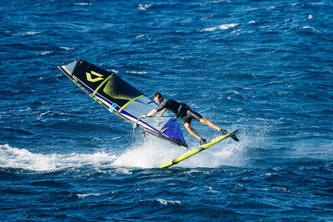 Duotone Idol freestyle windsurf sail during freestyle windsurfing on the ocean in navy and lime