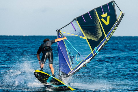 Duotone Idol freestyle windsurf sail during freestyle windsurfing on the open ocean in navy, blue and yellow-lime