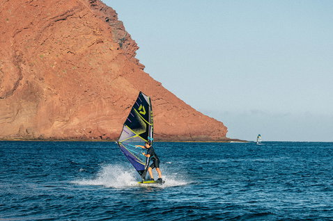 Duotone Idol freestyle windsurf sail during windsurfing at a volcanic rocky coastline