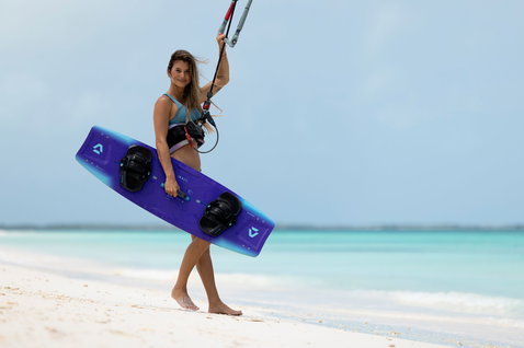 Tabla de kitesurf twin-tip Duotone Soleil Concept Blue durante el kitesurf en playa tropical en azul violeta