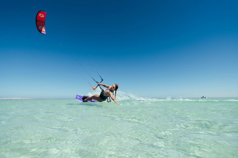 Tabla de kitesurf twin-tip Duotone Soleil Concept Blue durante kitesurf freeride en una laguna turquesa