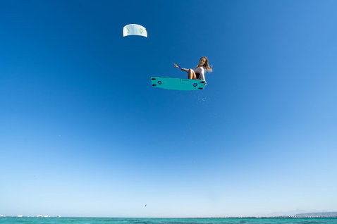 Tabla de kitesurf twin-tip Duotone Soleil Concept Blue durante salto aéreo de kitesurf sobre el océano