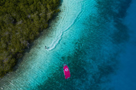 Planche de kitesurf twin-tip Duotone Entity 360 en corail lors d'une session kitesurf sur un lagon tropical