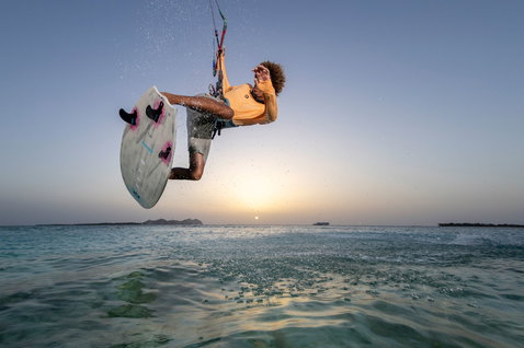 Duotone Volt D/LAB tabla de kite surf sin correas durante wave riding en laguna tropical al atardecer