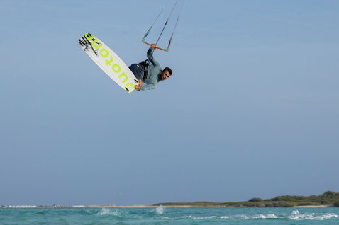 Duotone TS Big Air SLS Kiteboard beim Kitesurfen mit aerialem Grab-Trick über türkisfarbenem Wasser