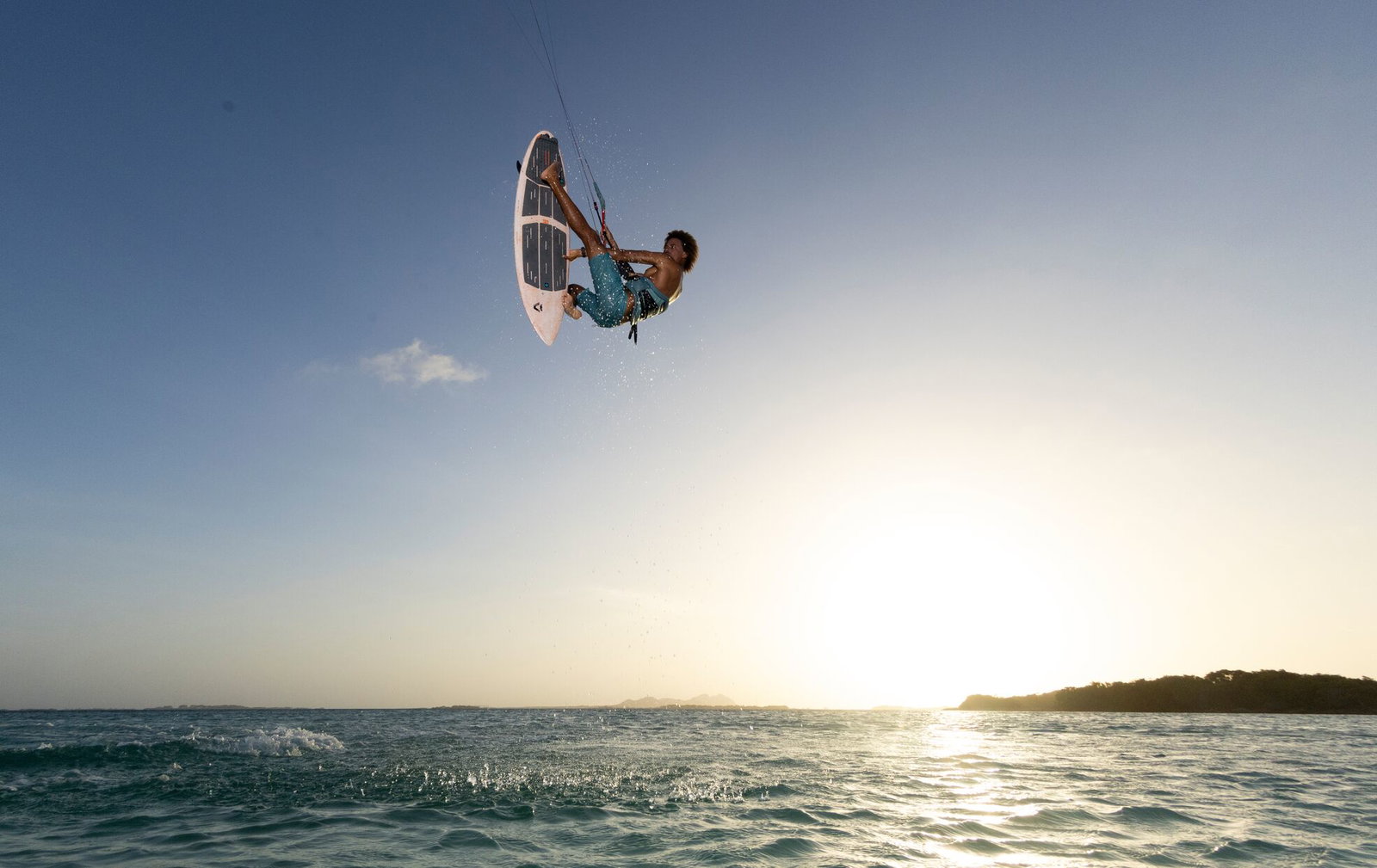 Duotone Blur SLS kite surfboard during strapless aerial kitesurfing at golden hour over tropical ocean