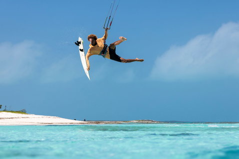 Tabla de kitesurf Duotone Whip SLS durante freestyle sin straps sobre una laguna tropical