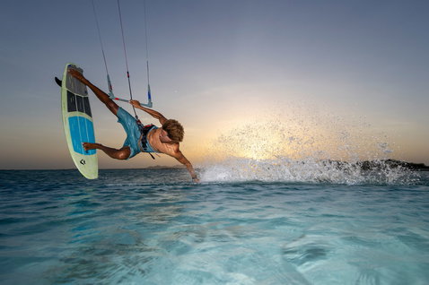 Duotone Whip SLS tabla de kitesurf durante freestyle sin trabas sobre agua turquesa en hora dorada
