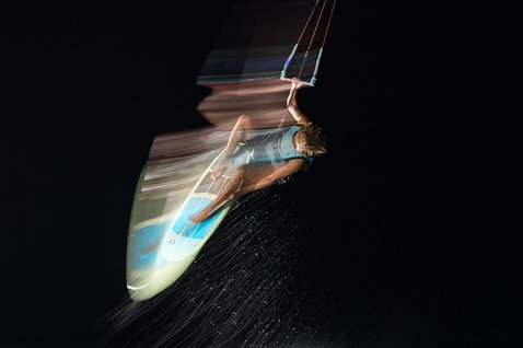 Tabla de kitesurf Duotone Whip SLS durante surf sin correas en el océano de noche