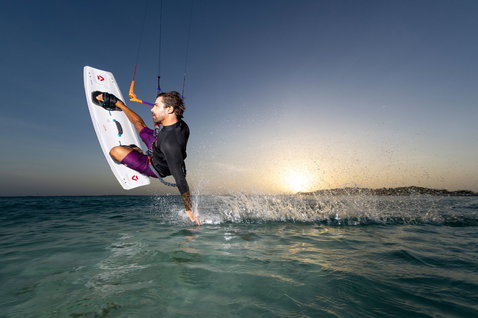 Planche de kitesurf twin-tip Duotone Entity Ergo Select lors d'un aérien au-dessus de l'océan tropical en heure dorée