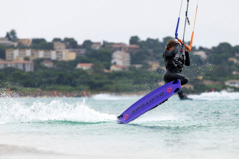 Tabla de kitesurf twin-tip Duotone Shred durante una sesión de kitesurf en bahía costera en morado