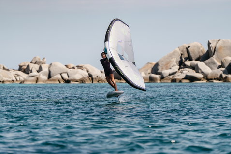 Duotone Skybrid Air foil board during wing foiling at a rocky coastal shore