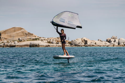 Duotone Skybrid Air foil board during wing foiling at a rocky coastal shoreline