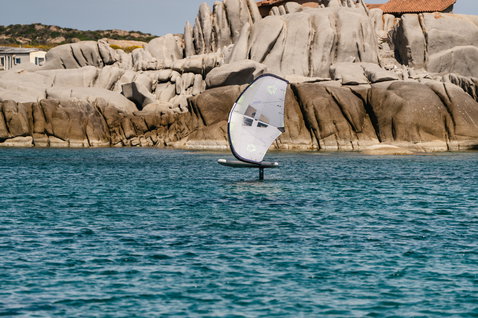 Duotone Skybrid Air wing foil board during wing foiling at a rocky Mediterranean coastal inlet