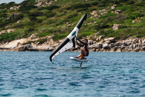 Duotone Skybrid Air foil board during wing foiling in a rocky coastal bay