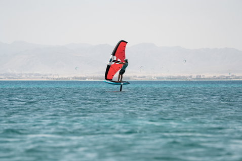 Duotone Sky Start DST Foilboard beim Wing Foiling auf dem Meer mit Bergpanorama