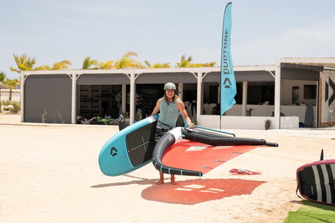 Duotone Sky Start DST Wing Foil Board beim Wing Foiling am Strand mit Anfängerin und rotem Foilwing